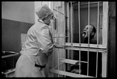 Nurse gives meds to prisoner behind bars in TB prison. The open mouth is to check the meds were swallowed. Image: Nachtwey. https://prisonphotography.org/tag/tuberculosis/